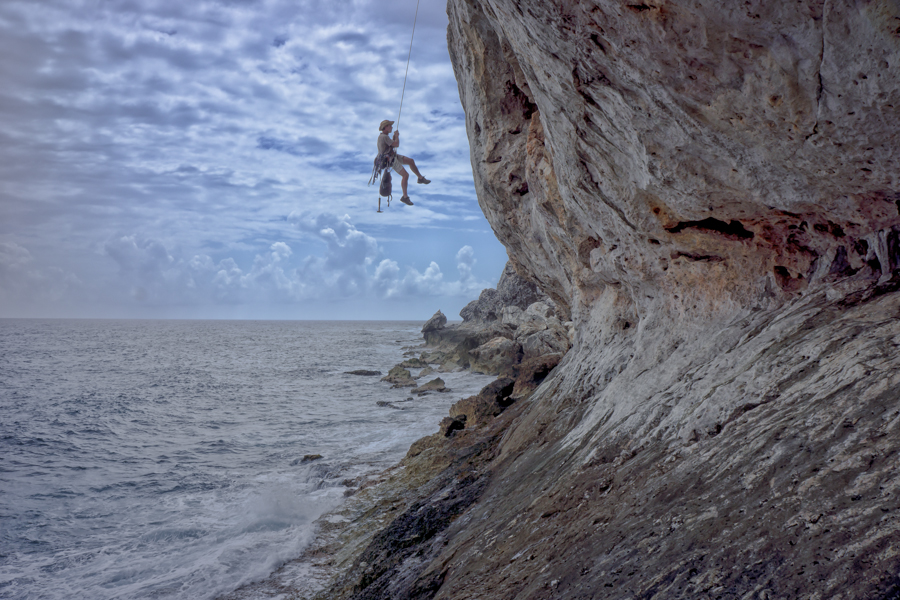 Rock climbing over tropical ocean waters.