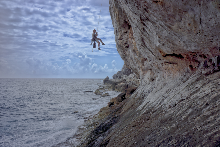 Rock climbing over tropical ocean waters. 